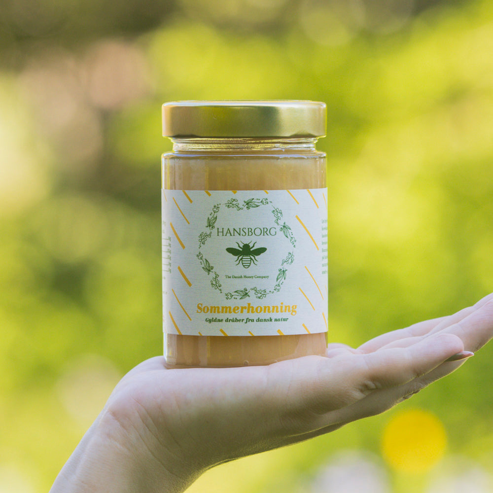 Hansborg mørk sommerhonning i glas sående på en hånd